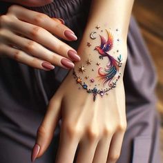 a woman's hand with a colorful bird tattoo on the wrist and stars around it