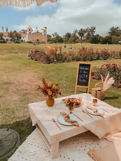 a table set up for a wedding reception in the middle of a field with flowers on it