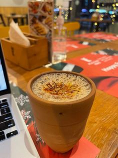 a cup of coffee sitting on top of a table next to a laptop