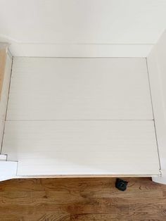 the bottom half of a bed with white walls and wood flooring on top of it