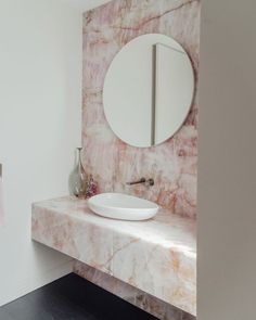 a white sink sitting under a round mirror in a bathroom next to a wall mounted faucet