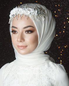 a woman wearing a white hijab with flowers on her head and pearls in the hair