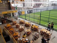 people are sitting at tables in the middle of an empty soccer field with yellow chairs