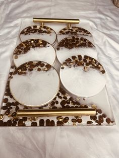 four plates with gold and white designs on them sitting on top of a white table cloth