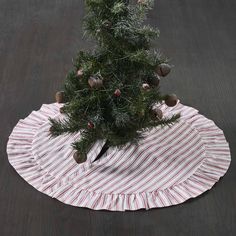 a small christmas tree sitting on top of a red and white striped tablecloth with pine cones