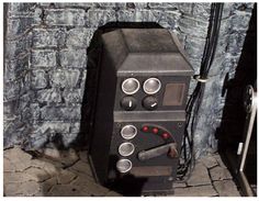 an old fashioned oven sitting in front of a stone wall with buttons on the knobs