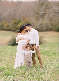 a couple and their son are standing in the grass