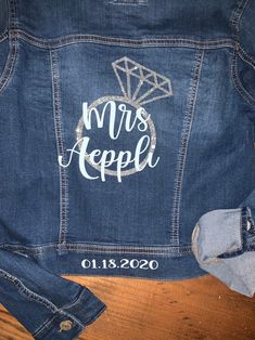 a denim jacket with the words mrs and her name on it, next to a pair of jeans