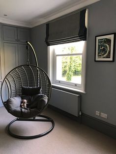 a room with a chair, window and dog on the swing in front of it