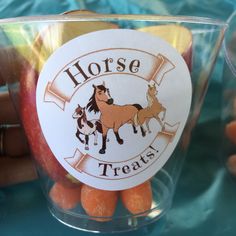 there is an apple and carrots in a cup with horse treats on it,