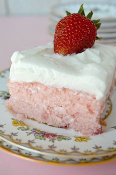 a piece of cake with white frosting and a strawberry on top is sitting on a plate