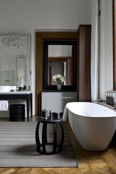 a bathroom with a tub, sink and large mirror in the corner on the wall