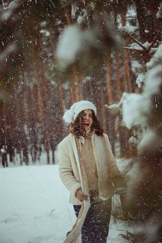 a woman is walking through the snow with a broom in her hand and wearing a white hat