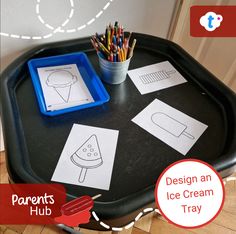 an ice cream tray with paper cutouts on it and pencils in front of it