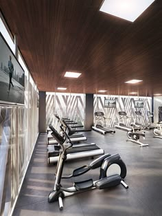 there are many treadmills in the gym with mirrors on the wall behind them