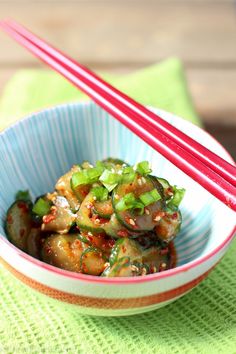 a bowl filled with vegetables and chopsticks on top of a green table cloth