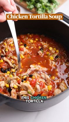 a person is spooning into a bowl of chicken tortilla soup with corn