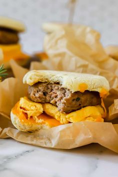 a sausage and egg breakfast sandwich is shown on wax paper with bananas in the background