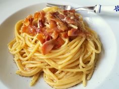 a white plate topped with pasta covered in bacon