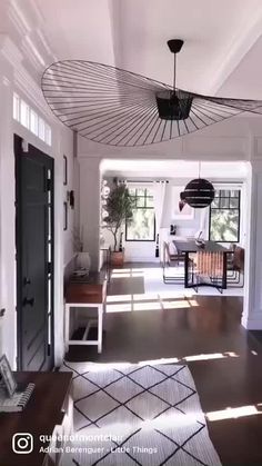 an open living room and dining area with white walls, wood flooring and black accents