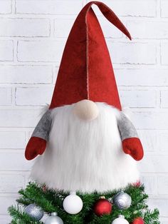 a christmas tree with a santa claus hat on it's head and ornaments around the base