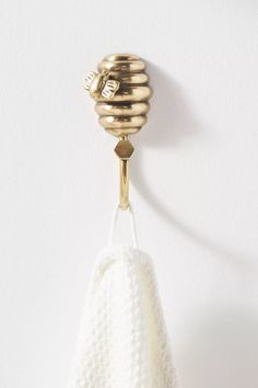 a white towel hanging from a hook on a wall with a gold colored object attached to it