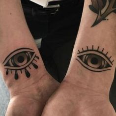 two people with matching tattoos on their wrists, one has an eye and the other has