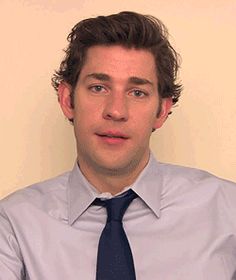 a man wearing a blue tie and white shirt looking at the camera with an intense look on his face