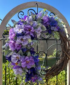 a wreath with purple flowers hanging on a gate