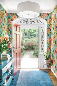 an entry way with floral wallpaper and blue rugs on either side of the door