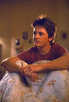 a man sitting on top of a bed in a bedroom