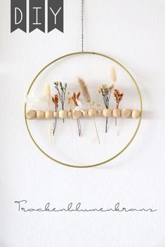 the diy project is made with wood beads and dried flowers on a circular frame