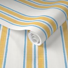 a yellow and blue striped wallpaper with a white roll laying on top of it