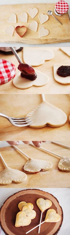 heart shaped cookies being made with cookie cutters on a wooden plate and spoon in the middle