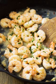 shrimp being cooked in a skillet with a wooden spoon