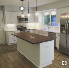 a kitchen with white cabinets and wood counter tops