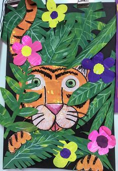 an animal made out of paper with flowers and leaves on the bottom, next to a cutout of a tiger's face