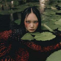 a young woman is floating in the water with lily pads