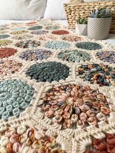 a crocheted blanket on top of a bed next to a wicker basket