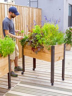 a man standing next to two wooden planters filled with flowers and plants in them