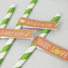 four green and white striped straws with brown paper labels on them that say, apple of my eye, sweet baby love