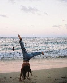 a person doing a handstand on the beach