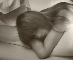 a woman laying in bed with her head on the pillow