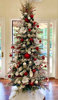 a white christmas tree with red and silver ornaments