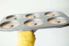 a person holding up a muffin tin with several cupcakes in it