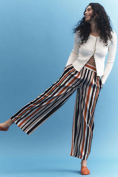 a woman with long hair is posing for the camera wearing striped pants and a white top