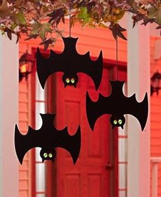 three bats hanging from a tree with eyes glowing in front of a red door at night