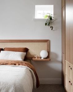 a bed sitting next to a window with a plant on top of it in a bedroom