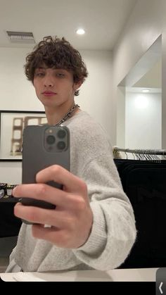 a young man taking a selfie with his cell phone in front of the camera