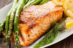 salmon and asparagus on a plate with lemon wedges